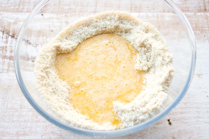 Ground almonds and whisked eggs and butter in a bowl.