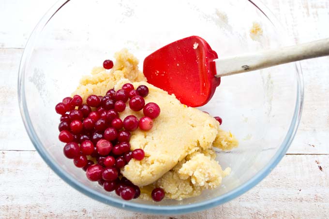 cranberries and dough in a bowl with a spatula