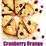 Cranberry orange scones on parchment paper with scattered cranberries and orange zest