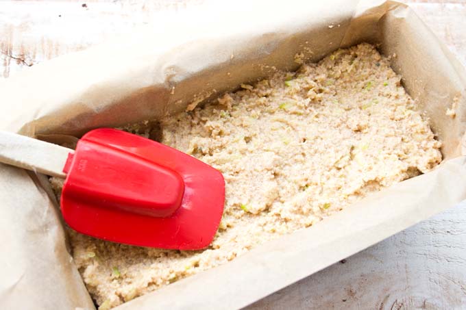 spreading the dough into a bread tin lined with parchment paper and smoothing the top with a spatula