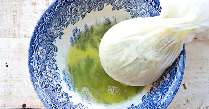 squeezing the liquid out of grated zucchini wrapped in a cheesecloth
