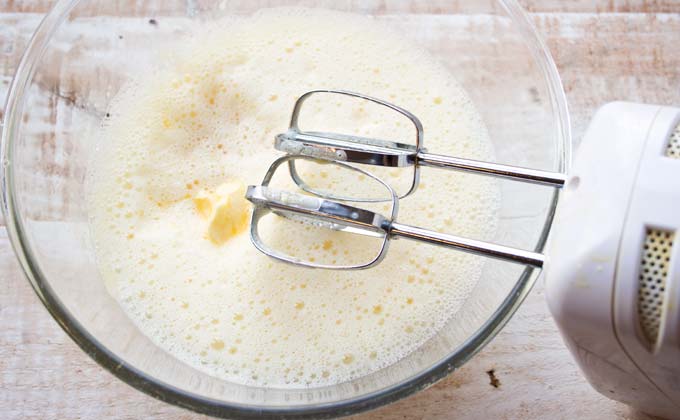 whisked eggs and butter in a glass bowl and an electric mixer