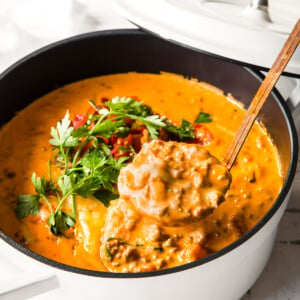 A saucepan with cheeseburger soup and a ladle.