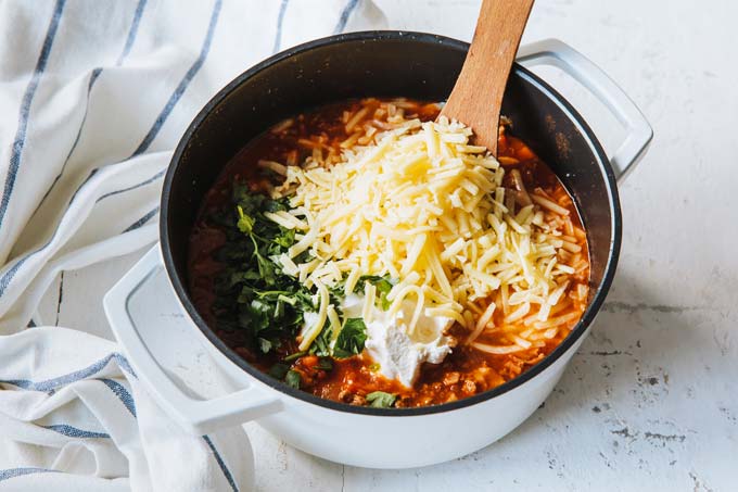 Adding grated cheese and other ingredients to the soup.