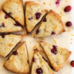 sugar free cranberry orange scones on parchment paper and scattered fresh cranberries