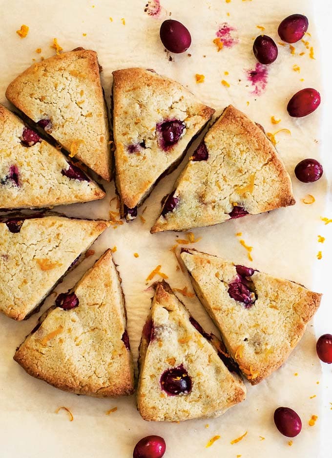 sugar free cranberry orange scones on parchment paper and scattered fresh cranberries
