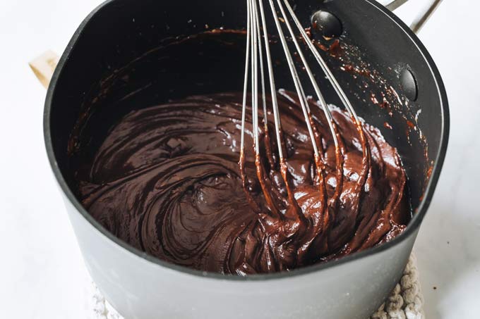 chocolate ganache in a pan with a whisk