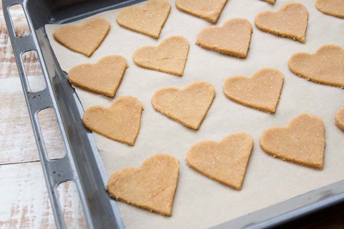 Unbaked heart shaped ginger cookies on a baking sheet. 