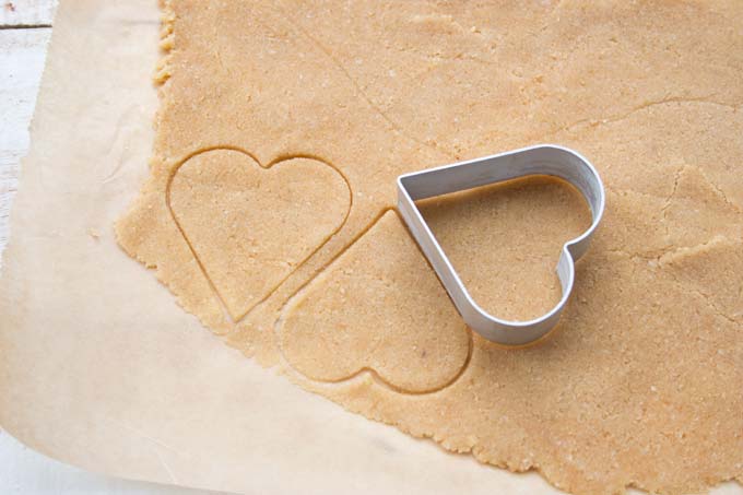 Stamped out heart shaped cookie dough and a cookie cutter.