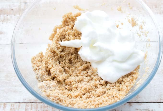 Cookie dough and stiff egg white in a glass mixing bowl.