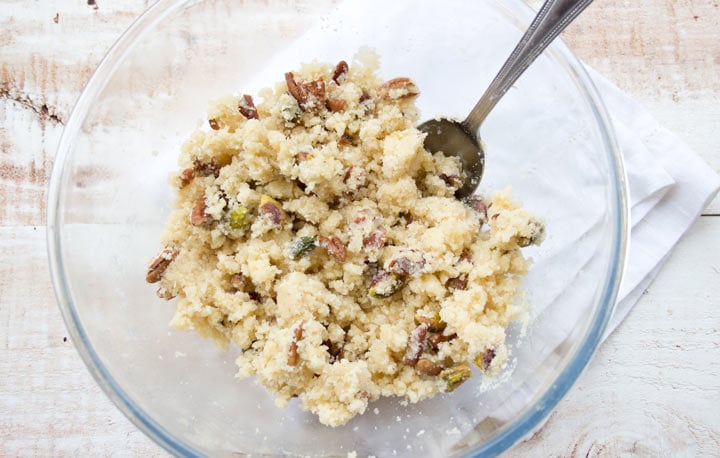 almond flour dough with pistachios and pecans in a glass bowl and a spoon