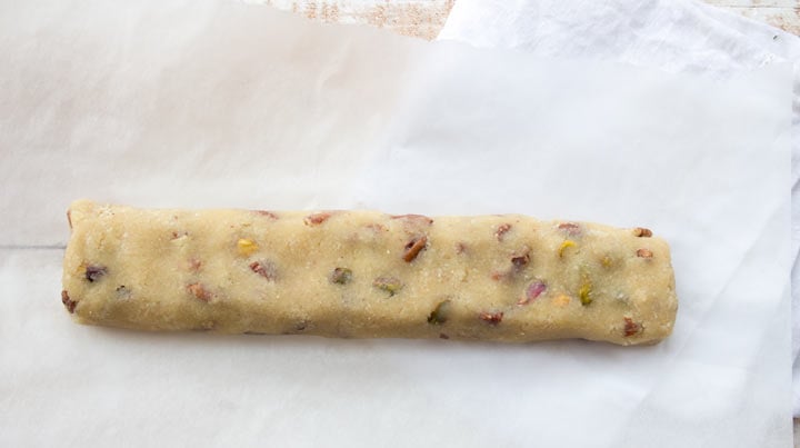 An unbaked cookie dough log on baking paper.