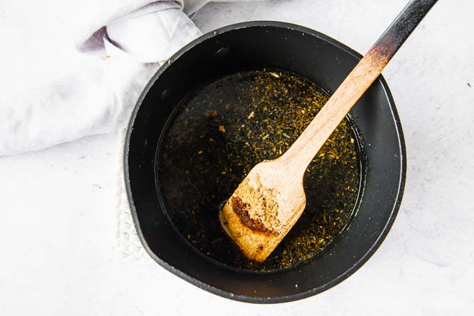 Adding tamari sauce to the fried ginger in a pan with a wooden spatula