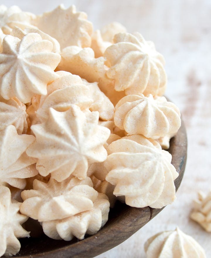 small meringue cookies piled high in a rustic bowl