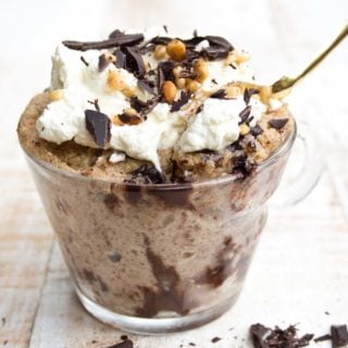 a keto mug cake with peanut butter topped with cream in a glass cup