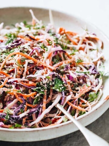 a coleslaw with red cabbage, white cabbage, carrots and herbs on a plate