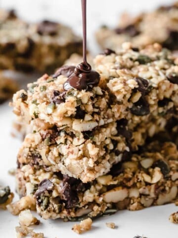 chocolate chip keto granola bar stack with chocolate being poured over it