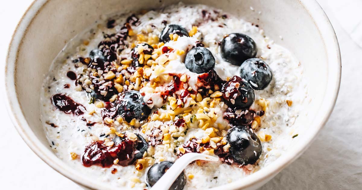 grain free oatmeal topped with berries and nuts and a spoon