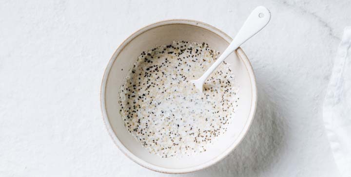 chia and hemp seeds in a bowl mixed with almond milk and a spoon