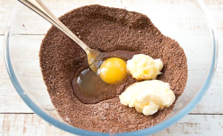 almond cocoa mix in a bowl with softened butter and an egg in a bowl
