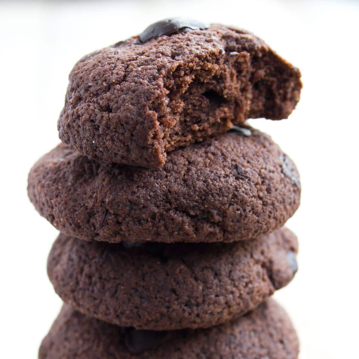 chocolate cookies stacked on top of one another, the top cookie is bitten into
