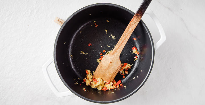 chopped garlic, ginger and chili in a frying pan with a spatula