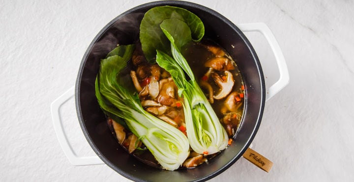 adding pak choi and vegetables into a saucepan