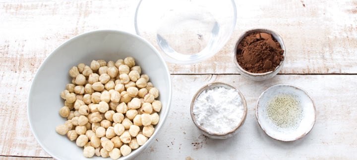 hazelnuts, sweetener, coconut oil, cocoa powder and vanilla extract in bowls