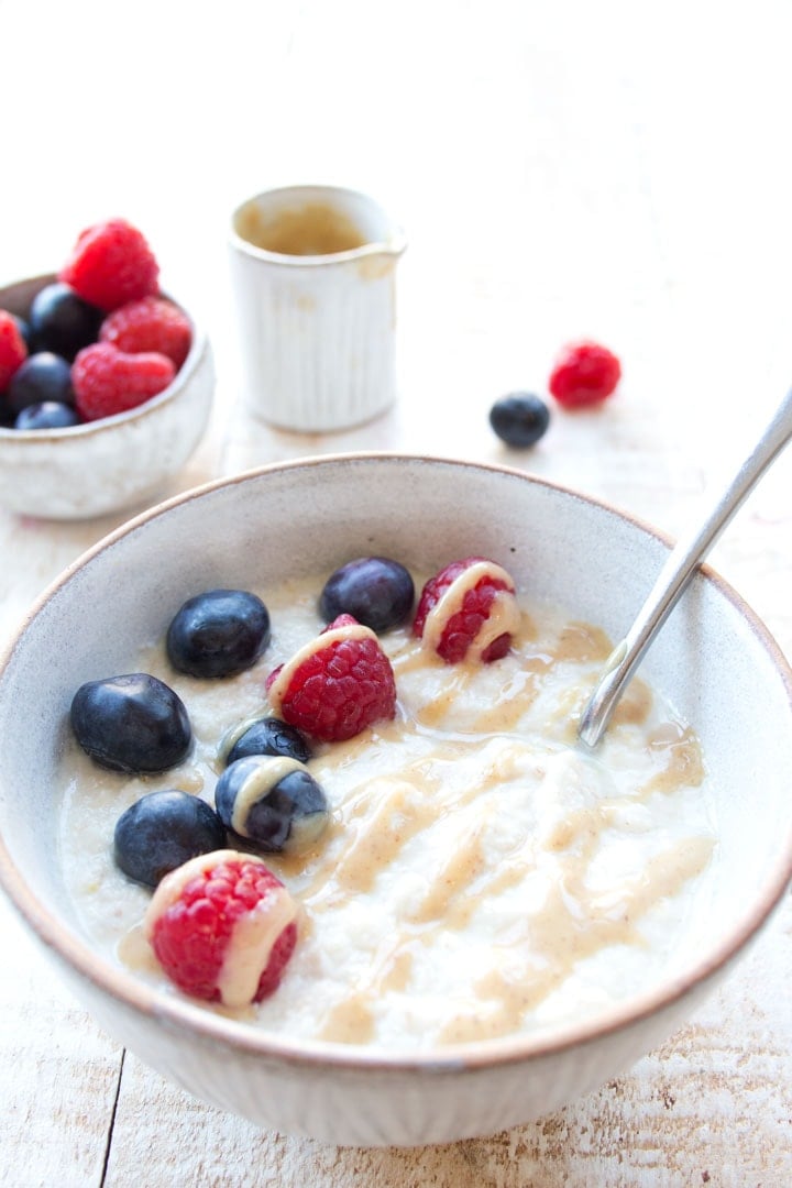 a bowl of keto oatmeal topped with berries and nut butter drizzle