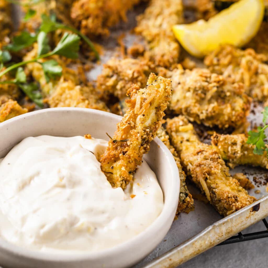 keto zucchini fries coated in almond flour and parmesan on a tray with a bowl of mayonnaise