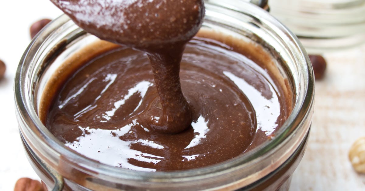 chocolate hazelnut spread dripping from a spoon into a glass jar