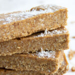 a stack of coconut almond butter bars topped with desiccated coconut