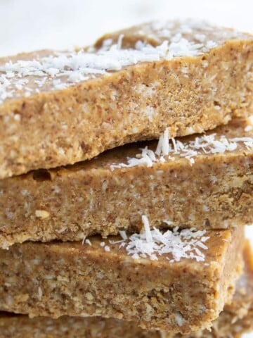 a stack of coconut almond butter bars topped with desiccated coconut