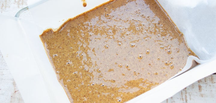 liquid almond butter and desiccated coconut mix in a pan lined with parchment paper