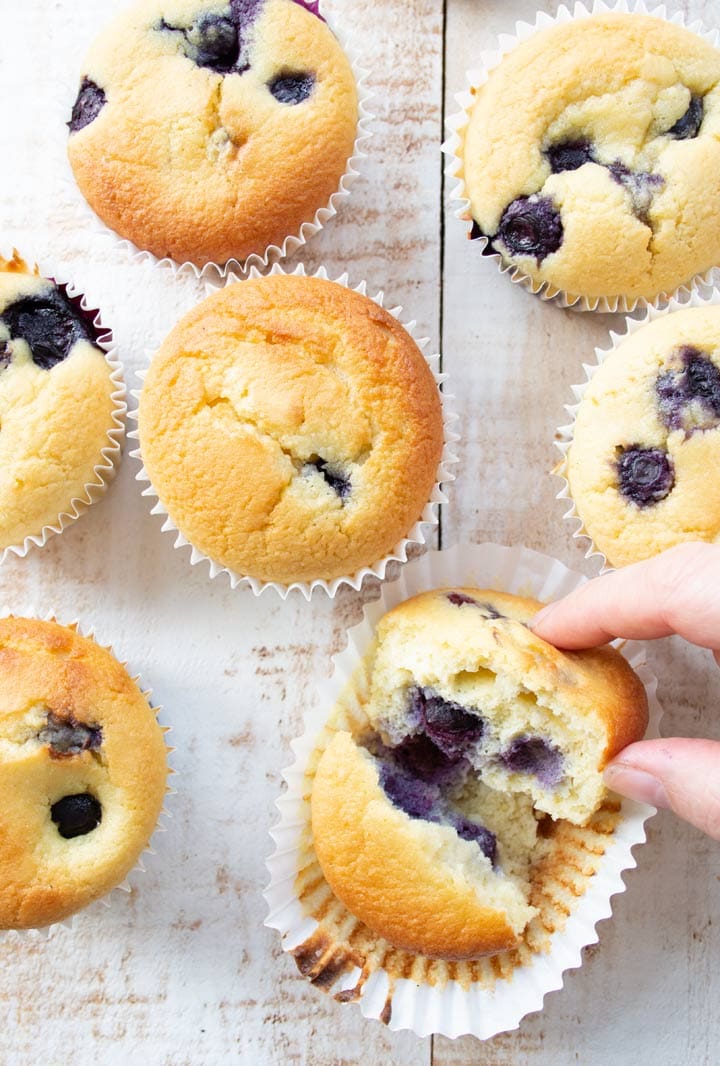 hand breaking a blueberry muffin in half