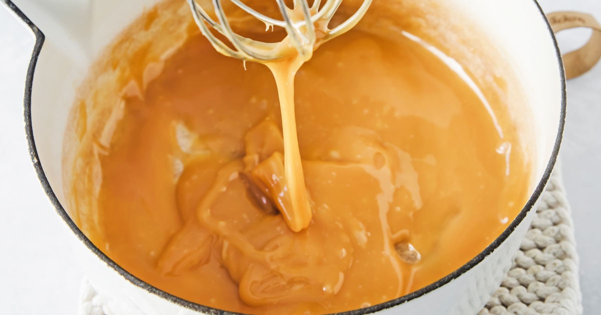 a saucepan with thick caramel sauce and a whisk