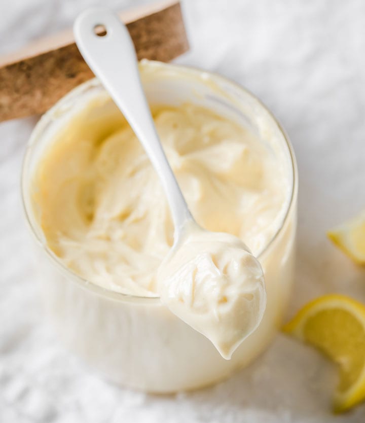 a spoon with mayo resting on top of a glass jar with mayonnaise