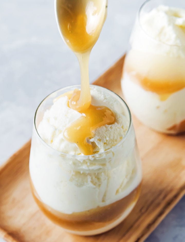 Caramel dripping off a spoon onto vanilla ice cream.