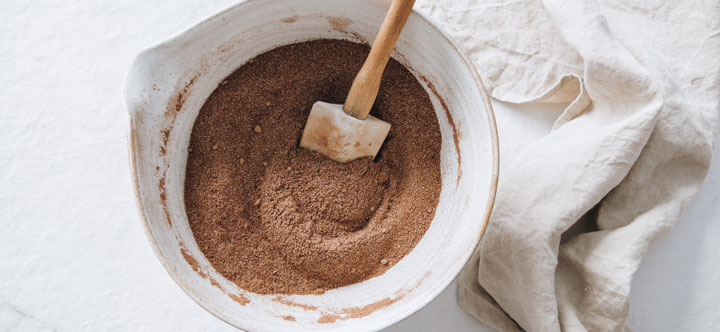 cacao powder and ogher dry ingredients mixed in a bowl with a spatula