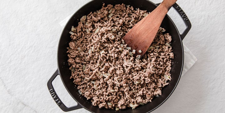 ground beef and chopped onions in a cast iron pan