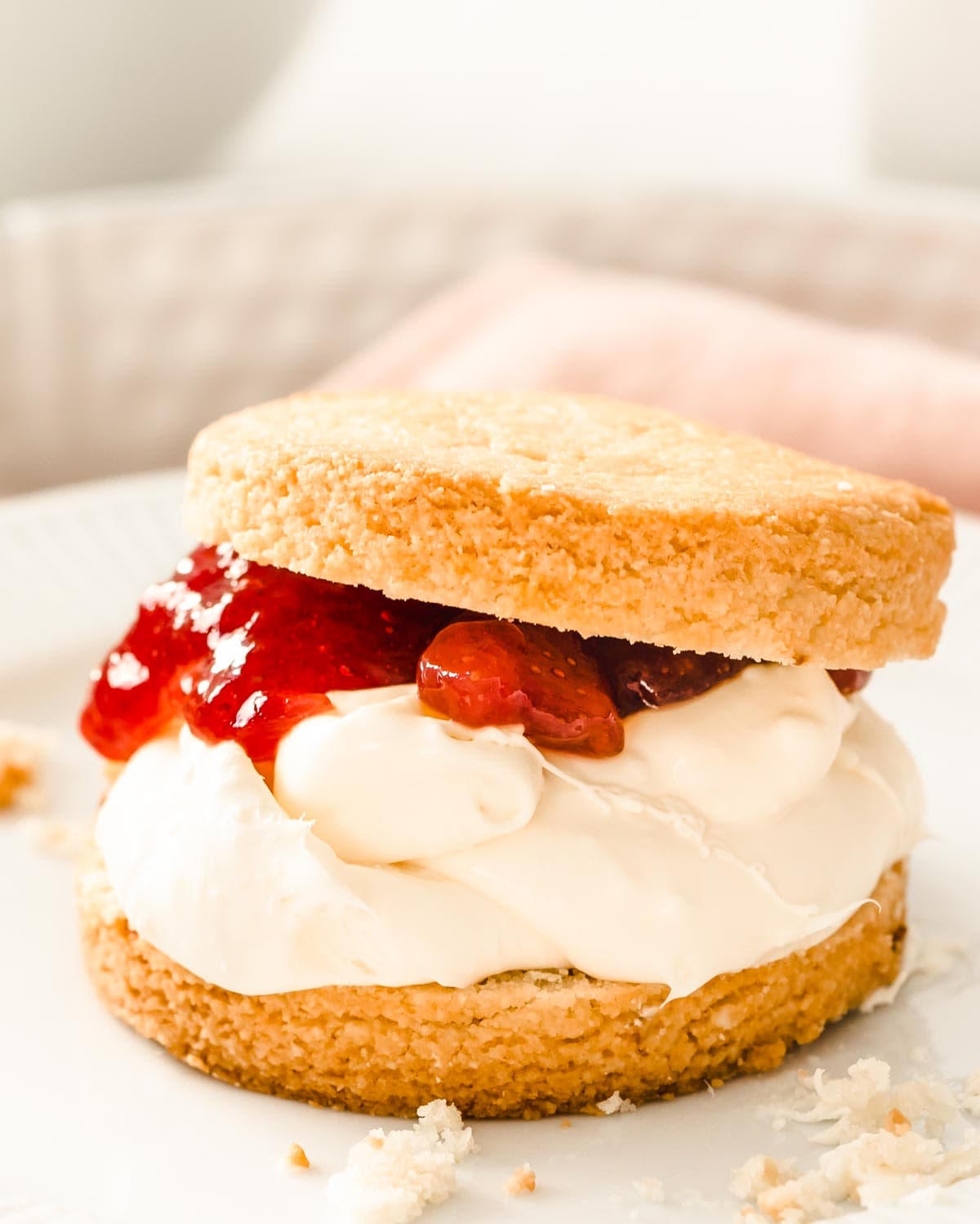 a keto scone made with almond flour cut in half and filled with clotted cream and strawberry jam on a white plate