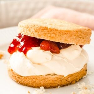 closeup of an almond flour scone cut in half and filled with clotted cream and strawberry jam