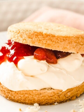 closeup of an almond flour scone cut in half and filled with clotted cream and strawberry jam