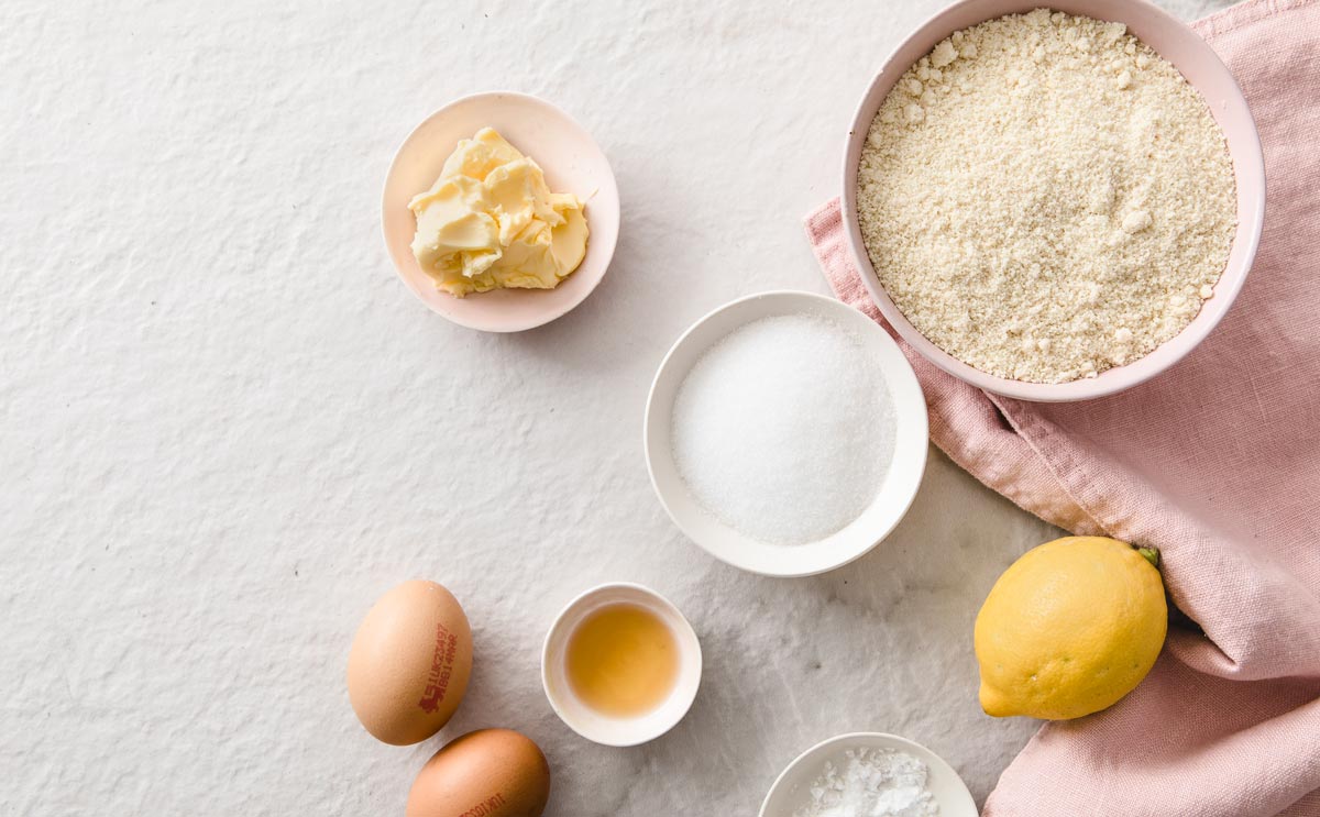 ingredients such as almond flour, erythritol, eggs, butter and lemon in bowls