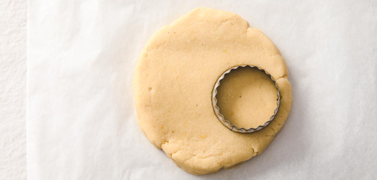 a dough disc and a round cookie cutter cutting scone shapes