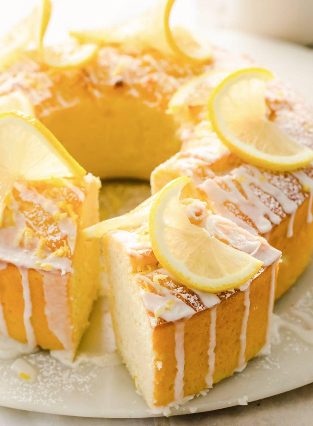 a keto lemon pound cake made in a bundt cake tin topped with coconut butter drizzle and lemon slices