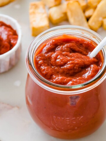 a glass jar of sugar free ketchup and a spoon and turnip fried in the background