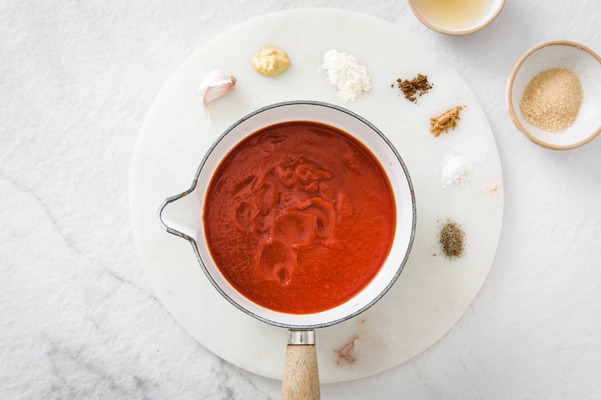 a pot with tomato puree and spices dotted around it