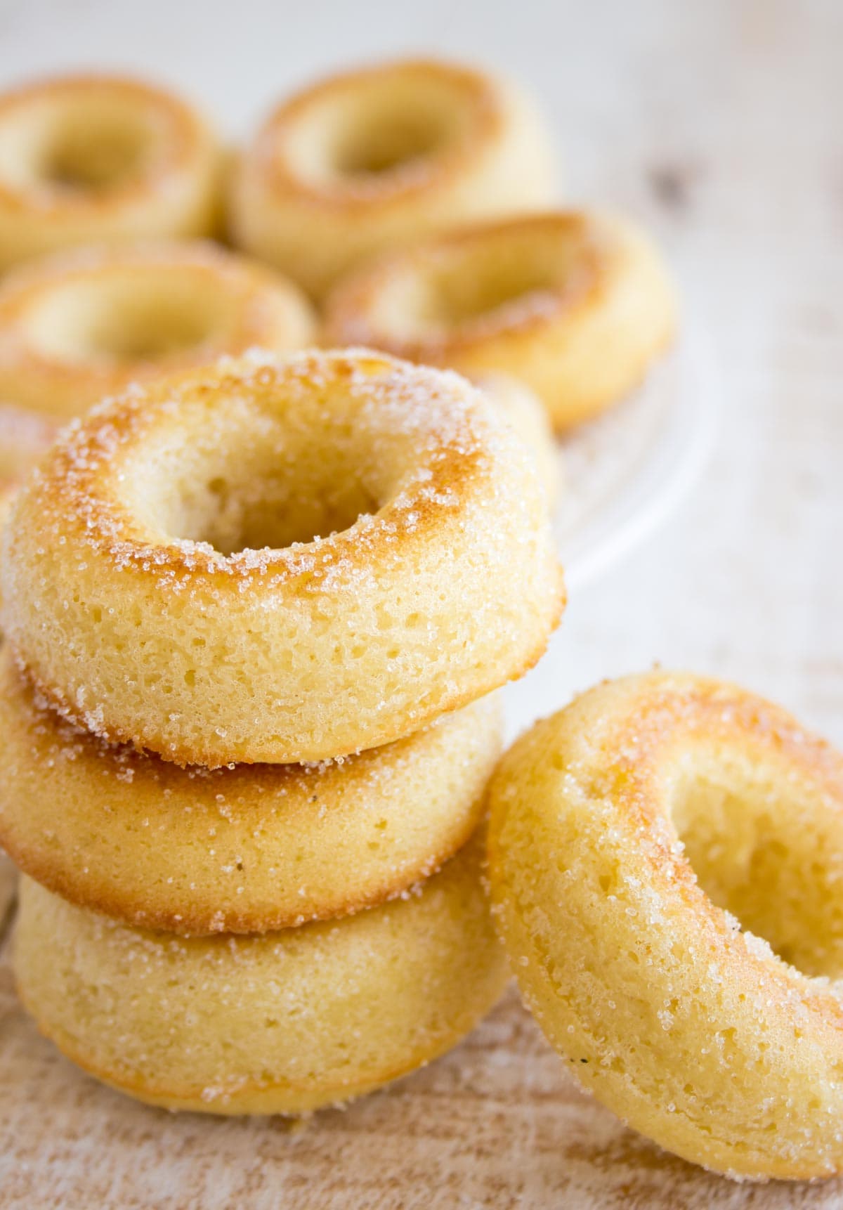 Three donuts coated in erythritol stacked on top of each other and another one leaning against the stack.