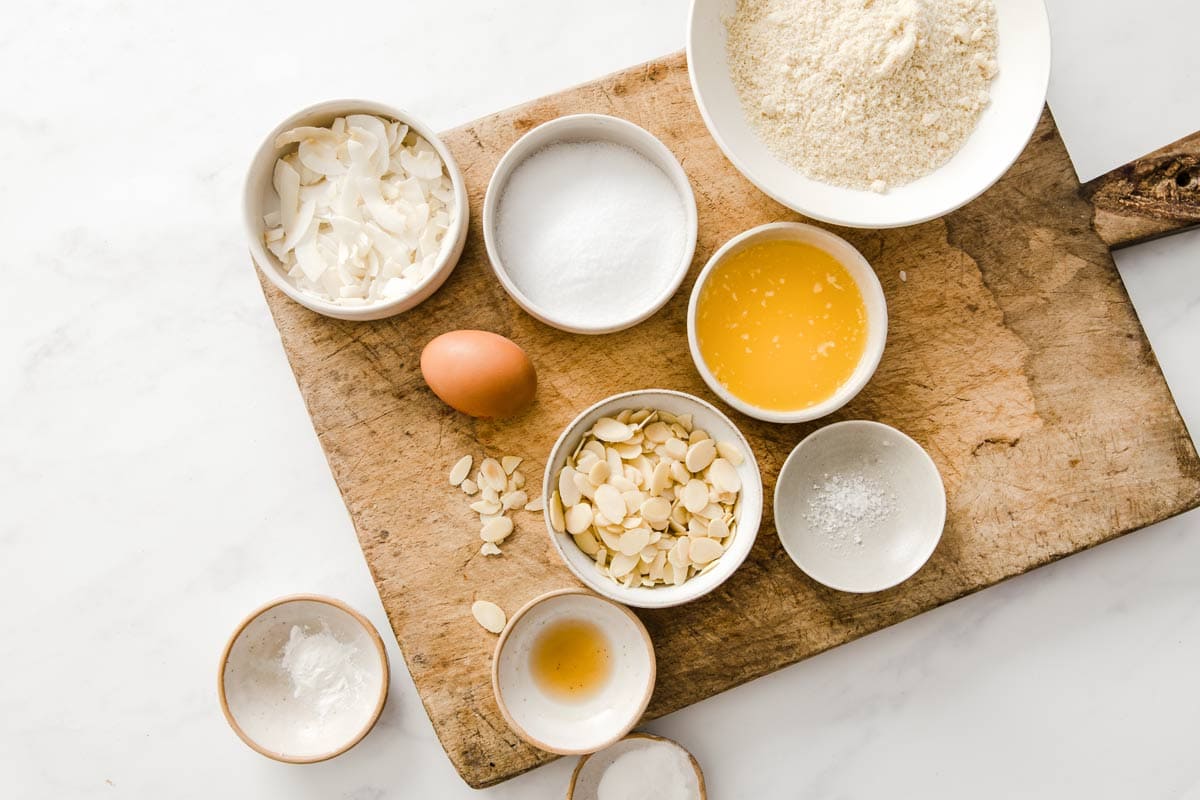 Cookie ingredients such as butter, almond flour, almond flakes and coconut chips in bowls.